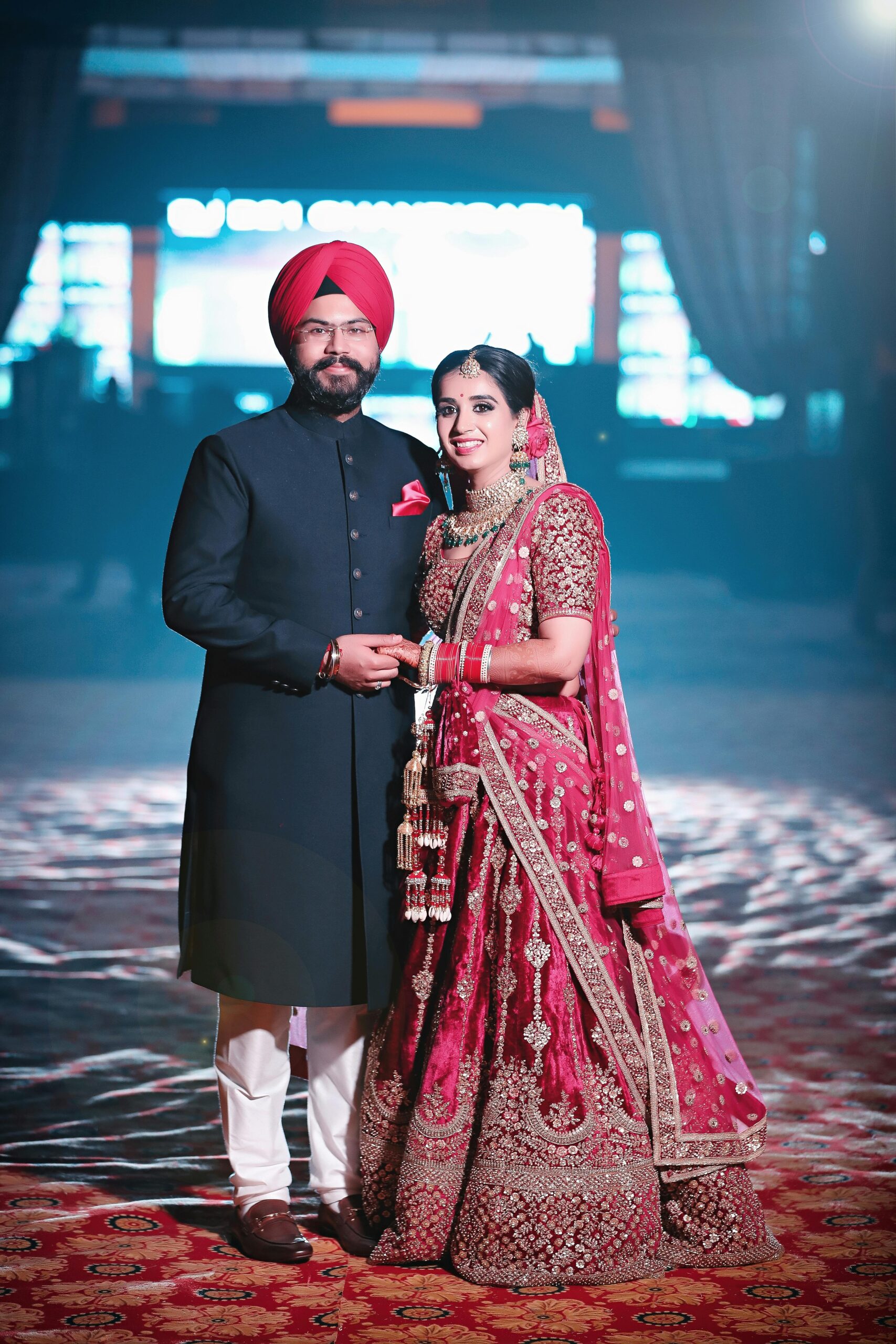 Home A joyful Indian couple in traditional wedding attire, celebrating their special day indoors.