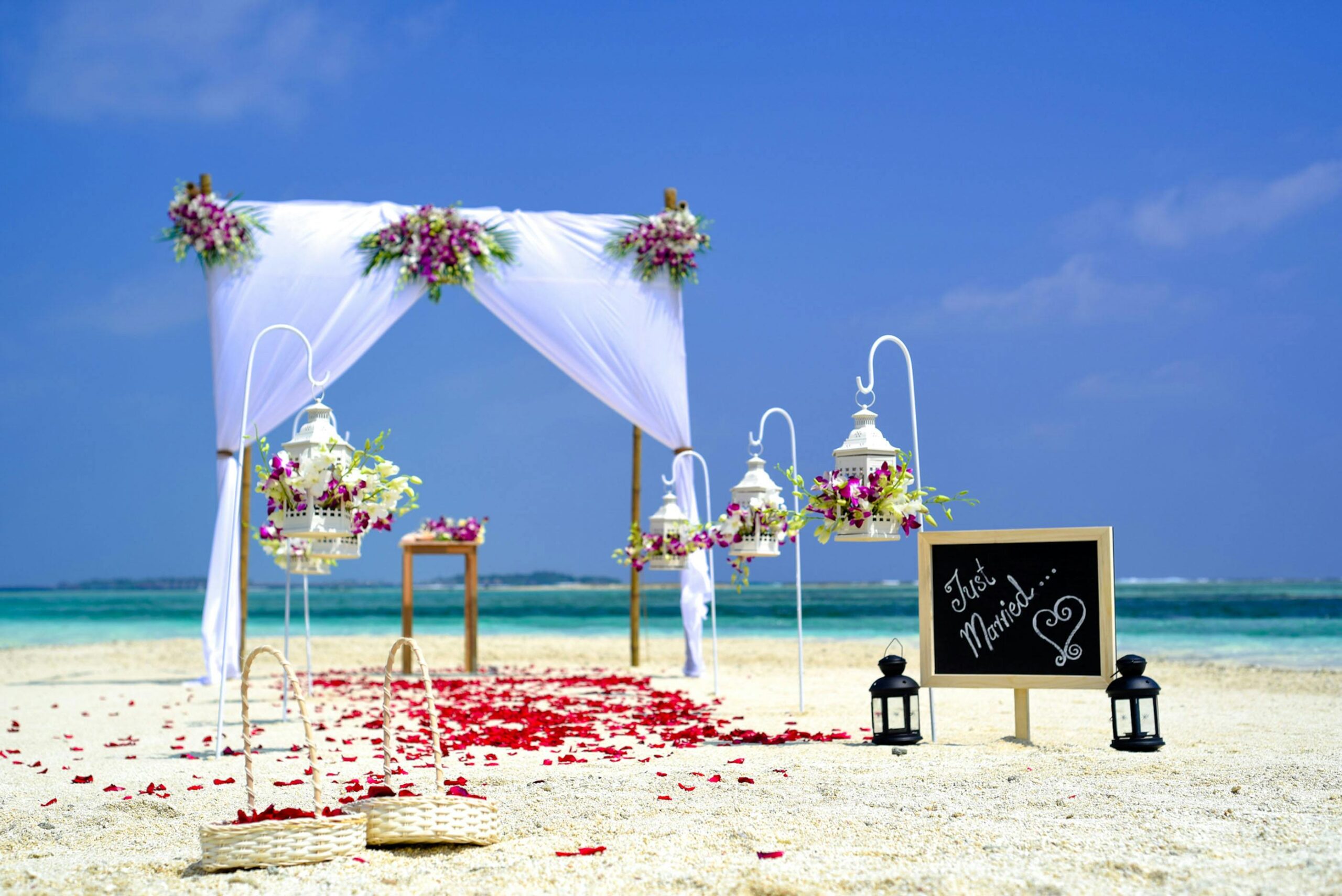 Home Stunning beach wedding arrangement with floral decor and lanterns on a sunny day.
