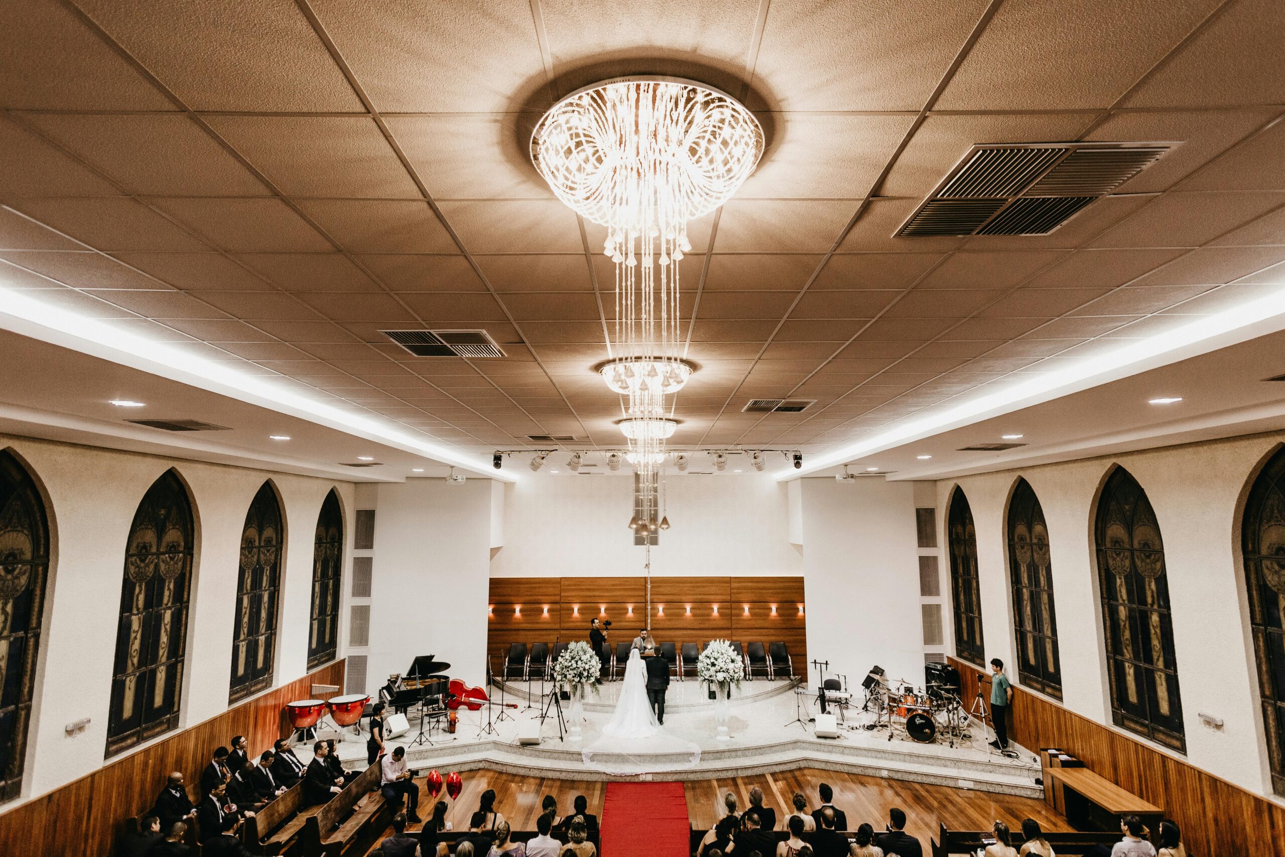 A beautiful indoor wedding ceremony with a stunning chandelier and guests seated, showcasing luxury and elegance.