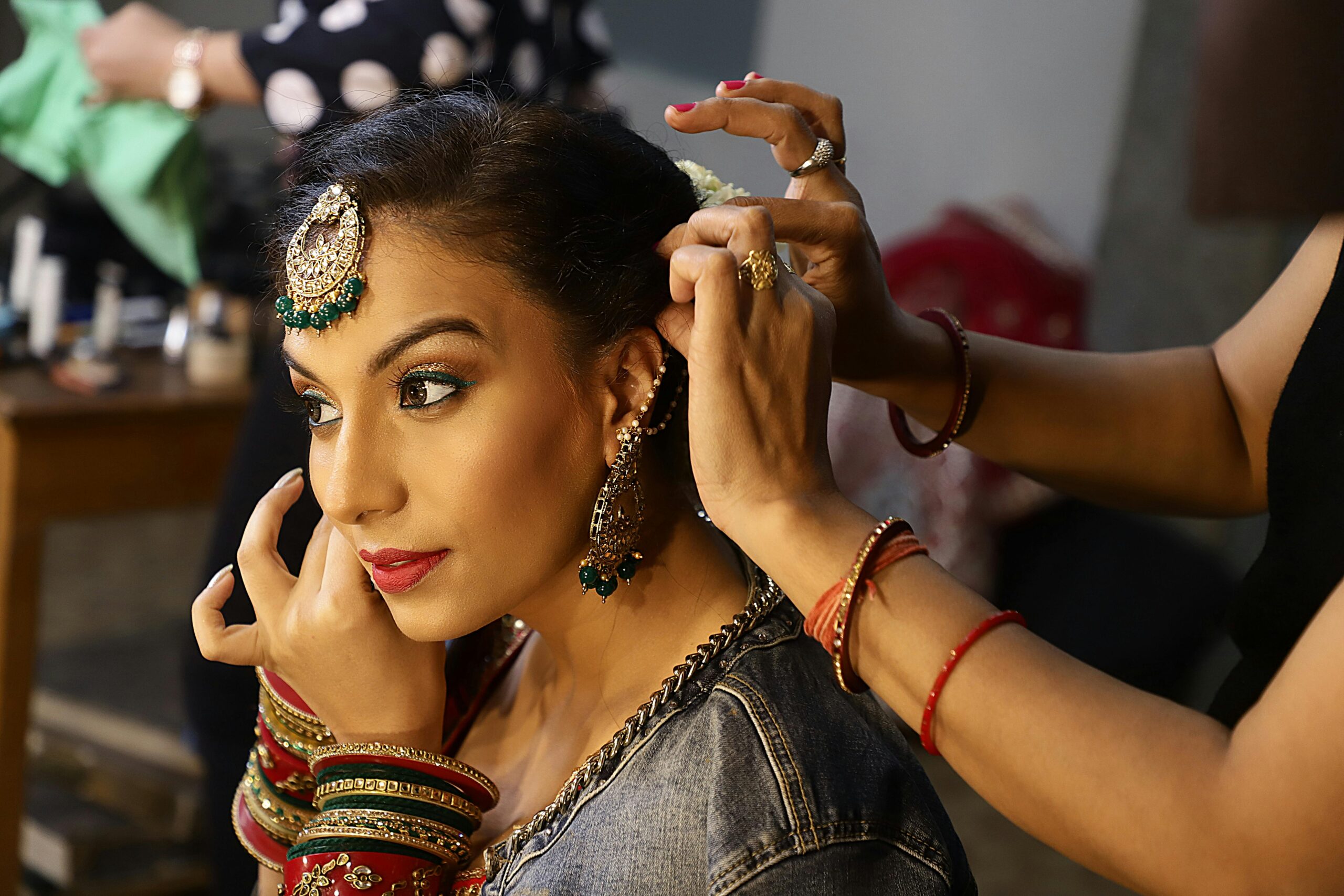 Services South Asian bride in traditional attire, getting ready with elegant jewelry and makeup.