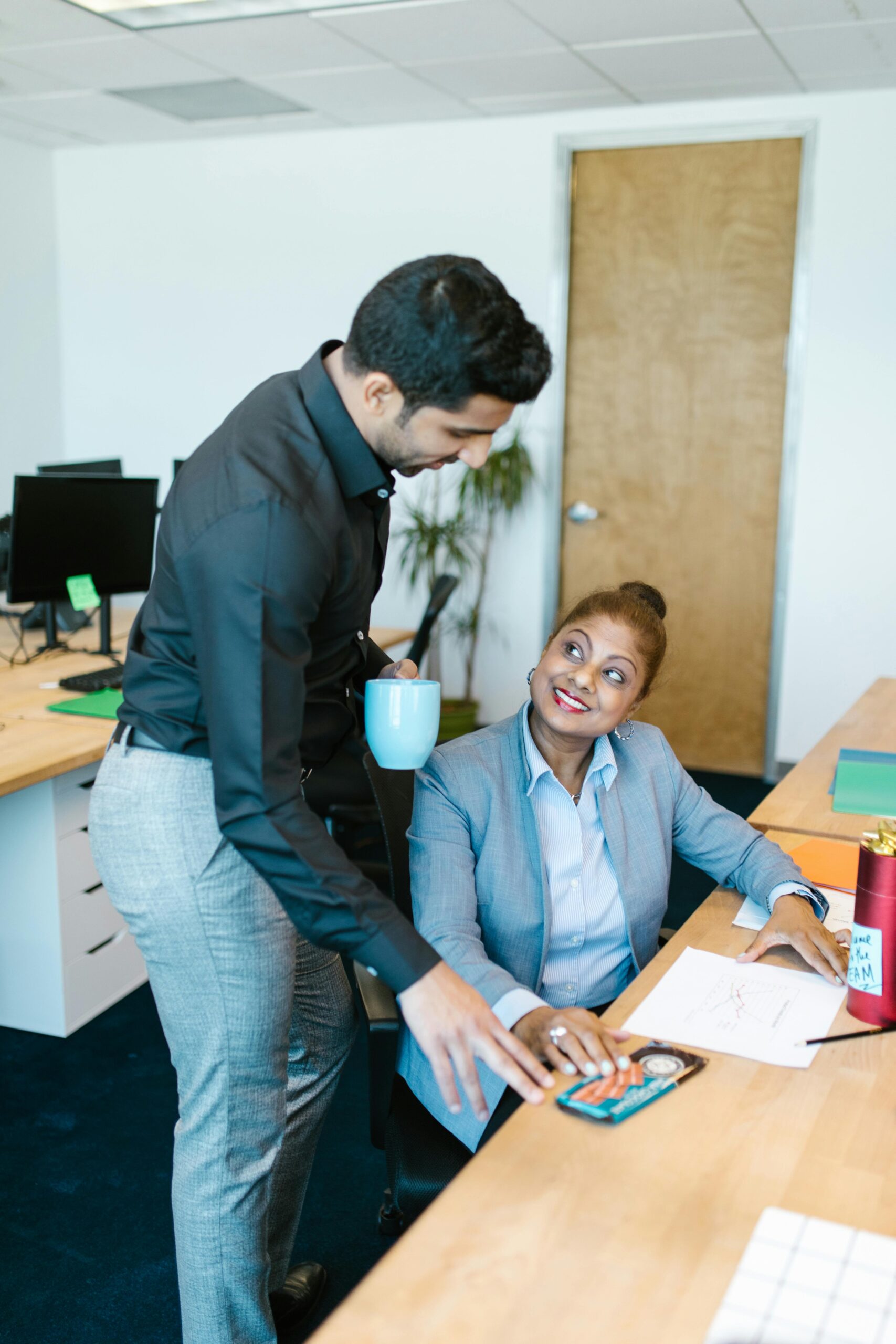 About Two colleagues collaborating in a bright, modern office environment, promoting teamwork and diversity.
